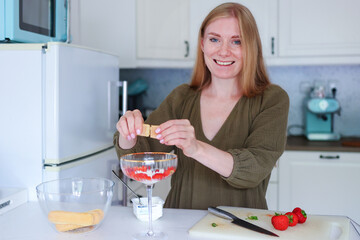 Homemade dessert creation, woman assembling creamy treat with fruit.