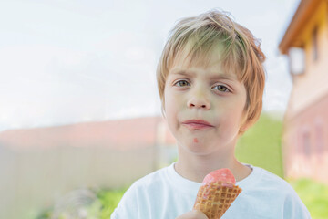 Boy eating raspberry ice cream in a waffle cup