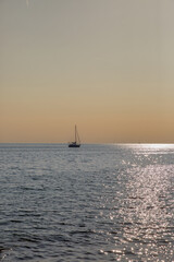 Sailboat silhouette on calm sea at golden hour sunset