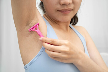 Asian young woman shaving armpit hair clean removal with razor after shower.