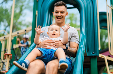 father with child boy is sitting on the slide with it