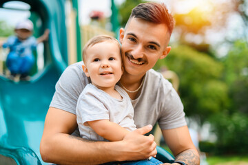 father with child boy is sitting on the slide with it