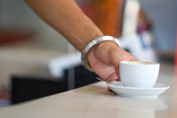 A Hand Reaches For A Cup Of Coffee On A Countertop With A Blurry Background Capturing A Relaxing Morning Moment