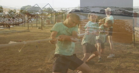 Four boys tugging rope at park field by wood posts and slide frame, with coastline overlay