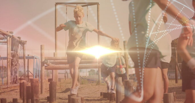 Jumping man crossing outdoor obstacle course, with children balancing on wooden posts