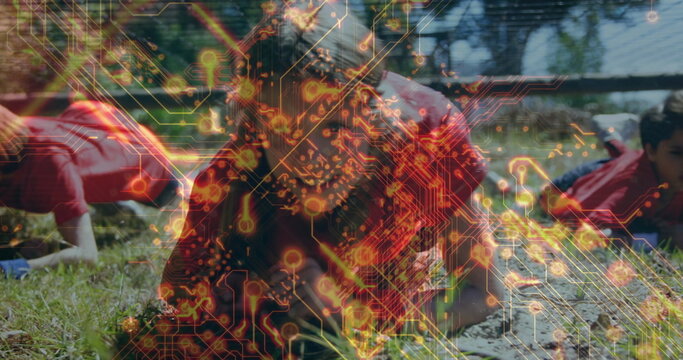 Crawling children wearing red sportswear under low net barrier on mud field, circuit board overlay