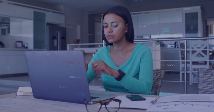 Working woman in teal top sorting charts by laptop in kitchen with phone glasses pen smartwatch - Powered by Adobe