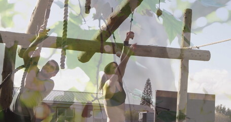 Gripping rope and reaching hanging log, partners navigating wooden obstacle course in sportswear