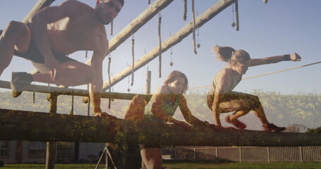 Navigating shirtless man and women in sportswear on wooden beam in outdoor course with ropes