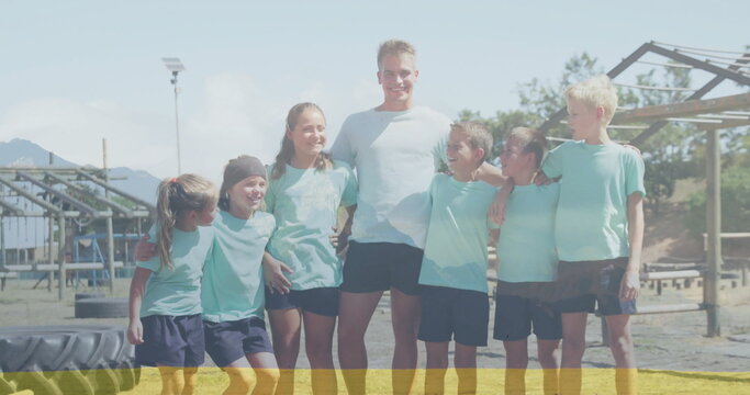 Standing together coach and children wearing teal sportswear at obstacle course, with tractor tire
