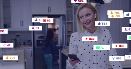 Streaming live woman wearing polka-dot blouse and earbuds holding smartphone in kitchen, copy space