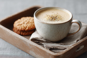 Chai tea latte served with biscuit looks so inviting and delicious on wooden tray