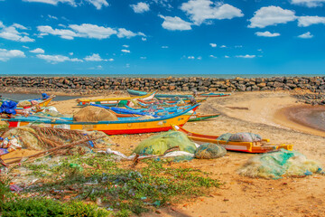 Vibrant Fishing Boats Resting on Sandy Beach with Seawall in Background