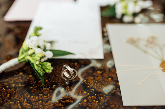 Wedding details on the small table. Cute rings, invitation card and flowers