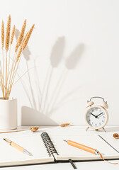 Cozy desk setup with open notebook pencils and alarm clock