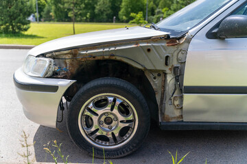 Damaged rusty car parked on the street showing mechanical problems