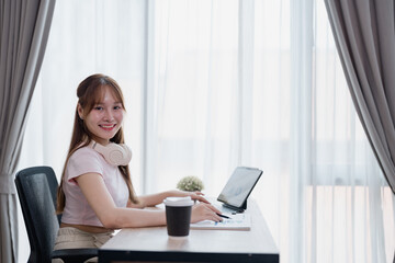 Happy businesswoman working from home, managing her business, sitting at a desk, using laptop and...