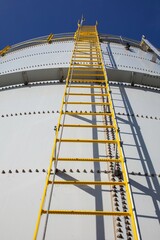 looking up at large water tank with yellow stairs and blue sky
