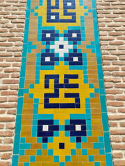 Colorful tile mural with geometric patterns on a textured brick wall showcasing vibrant artistry