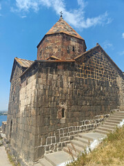 Ancient monastery by Lake Sevan in Armenia with panoramic views, clear sky, and visitors exploring...