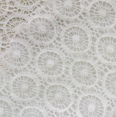 Zoom sur de la dentelle blanche délicate dans un atelier de couture, mettant en valeur la finesse...