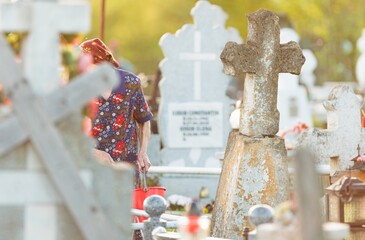 In the warmth of the setting sun, an older woman, dressed in a floral print outfit, carefully tends...