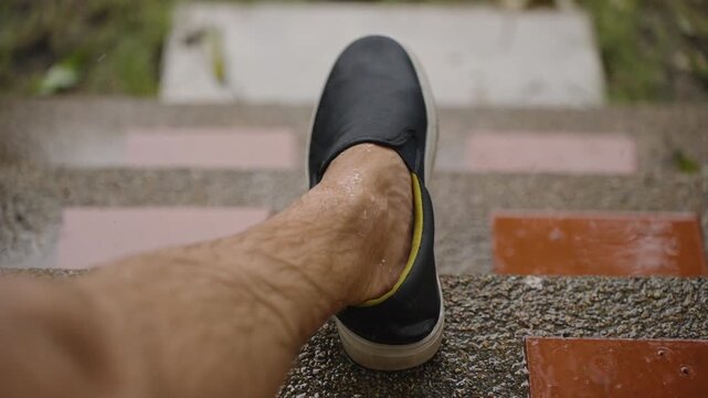 Man&rsquo;s Wet Foot Wearing Black Shoe Resting on Rainy Steps During Tropical Downpour in Slow Motion, Contemplative Mood Concept
