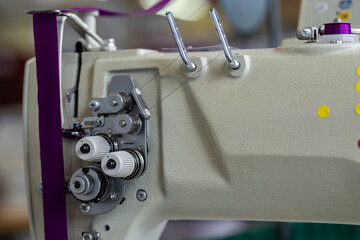 Zoom sur une partie d’une machine à coudre montrant le fil soigneusement enroulé sur la bobine, prêt à être utilisé pour la couture.