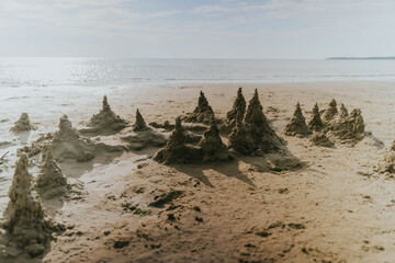 Sandcastle kingdom rising on sunny beach: conical towers sculpted from wet sand