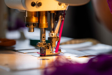 Zoom sur une machine à coudre en pleine action dans un atelier de couture, avec l’aiguille en...