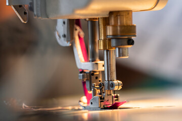 Zoom sur une machine à coudre en pleine action dans un atelier de couture, avec l’aiguille en...