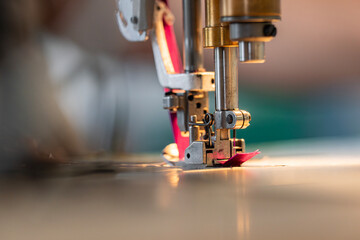 Zoom sur une machine à coudre en pleine action dans un atelier de couture, avec l’aiguille en mouvement sur un tissu, illustrant le travail de confection artisanale.