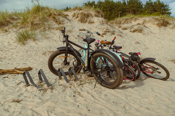 Bicycles resting on sandy beach by dune after ride