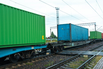 Freight train carrying colorful cargo containers on railway tracks