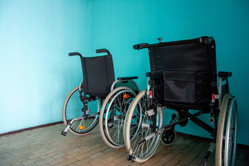 Two empty wheelchairs parked against turquoise wall representing disability and accessibility issues