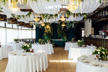 Luxurious restaurant. Luxurious interior, white tables, serving dishes and glasses for guests....