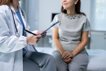 A woman is sitting on a hospital bed while a doctor talks to her