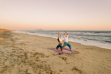 Couple Practicing Yoga on Beach at Sunset