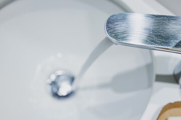 Fresh water flowing from a brushed chrome faucet into a pristine white sink, capturing the essence...