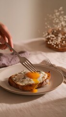 Close-up of a Croque Madame being cut with a fork, yolk spilling onto crisp toast