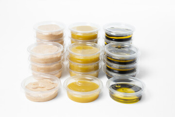 Assorted sauces in transparent plastic containers with lids on a white background. Includes light...