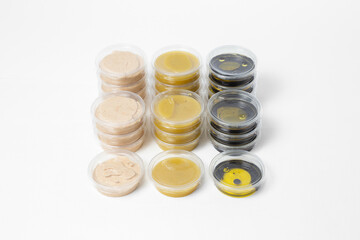 Assorted sauces in transparent plastic containers with lids on a white background. Includes light...