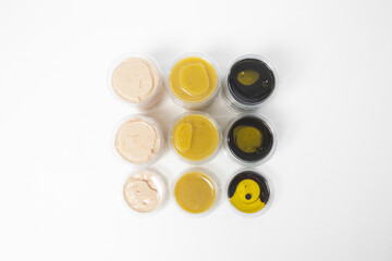 Assorted sauces in transparent plastic containers with lids on a white background. Includes light...