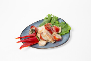 Baked fish fillet with tomatoes and cheese, served with pepper and salad on a plate on a white background