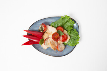 Baked fish fillet with tomatoes and cheese, served with pepper and salad on a plate on a white background