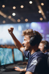 Ecstatic gamer celebrating victory, fist raised in triumph at a competition. Captures success, skill, and passion. Ideal for technology, esports, and achievement themes.