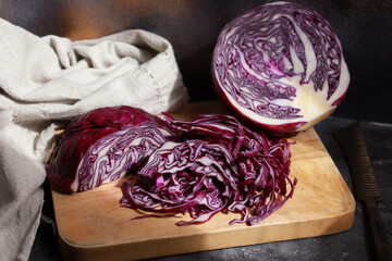 Shredded purple cabbage on  wooden cutting board.