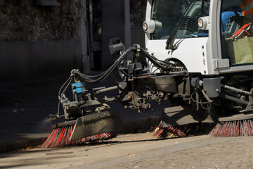 close-up, detailed shot focuses on the side brushes and cleaning mechanisms of a white street...