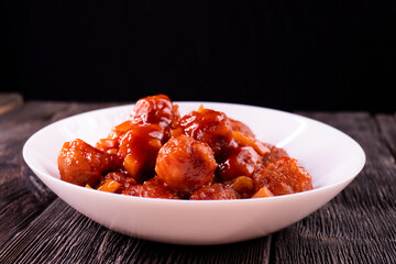 Meatballs with pineapple in sweet and sour sauce on wooden background. Chinese food. Asian cuisine