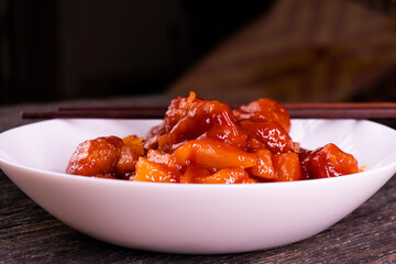 Meatballs with pineapple in sweet and sour sauce on wooden background. Chinese food. Asian cuisine